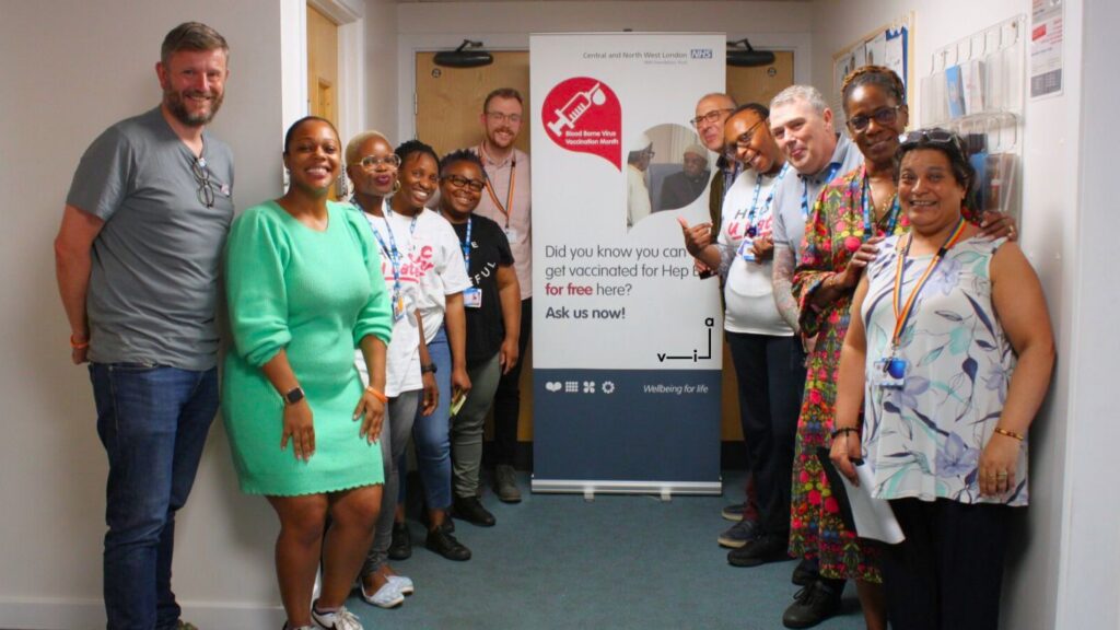 A group of people smiling and standing around a banner at one of our Brent services.