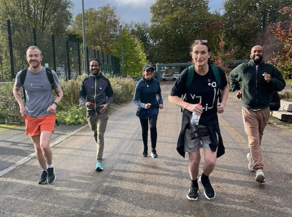 Four people in active wear smiling and running towards the camera.