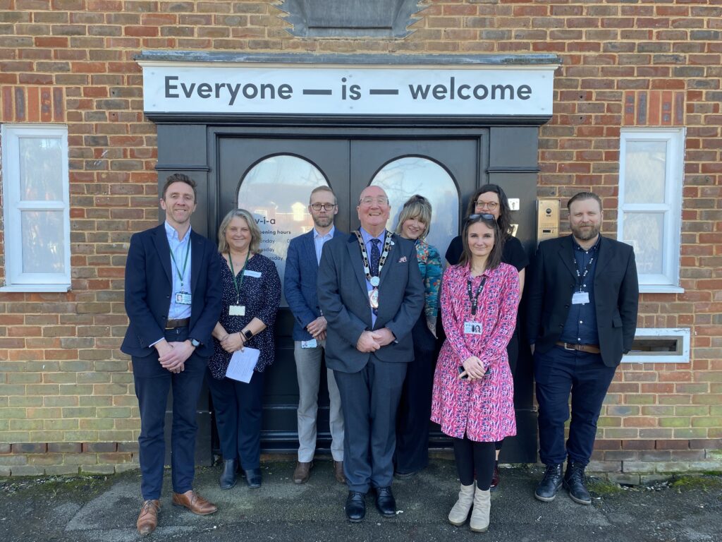 group of people standing outside building with double doors and text above reading 'Everyone-is-welcome'